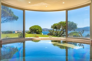 A pool with a clear view of the surrounding landscape, including trees and a body of water. - Holiday House - 5 people, 22 m² living space, 2 bedroom, Internet/WIFI, Internet access (Cannigione di Arzachena)