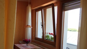 A dining area with a table, chairs, a vase with flowers, and a window with a view of the outside. - Apartment at the castle Eltz (Wierschem)