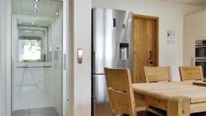 Una cocina moderna con un refrigerador de acero inoxidable, una mesa de comedor de madera y sillas.