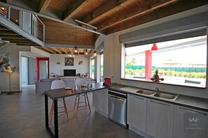 A modern kitchen with a large island, stainless steel appliances, and a view of the outdoors.