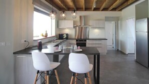 A modern kitchen with a central island, stainless steel appliances, and a wooden ceiling.
