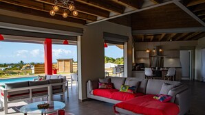 A spacious living area with a pool view, a dining area, and a kitchen.