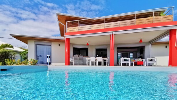 A modern house with a swimming pool, outdoor seating, and a wooden deck.