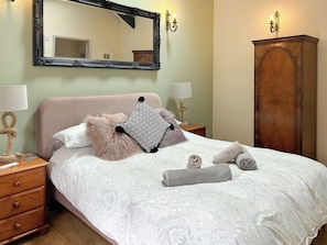 A neatly made bed with a patterned bedspread, two pillows, and rolled towels.