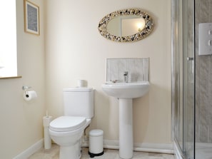 A bathroom with a toilet, sink, and a mirror with a decorative frame.