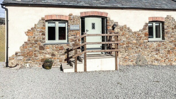 A stone building with a wooden staircase leading to a door marked 'Nuthatch.'