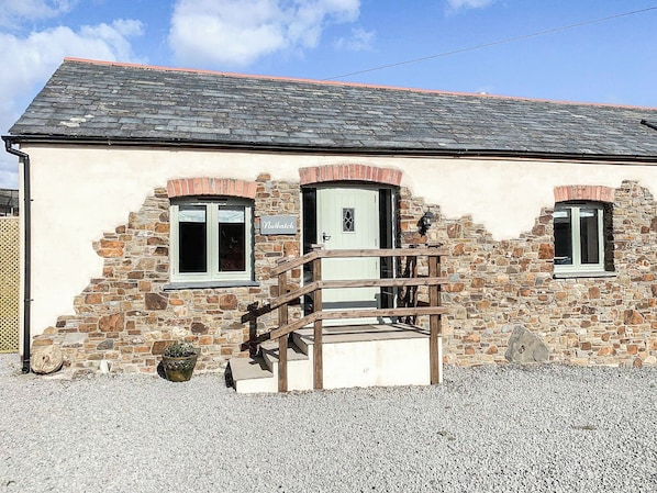 A stone building with a wooden staircase leading to a door marked 'Nuthatch.'