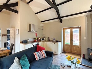 A living room with a dark sofa, a kitchen with white cabinets, a microwave, and a fireplace.
