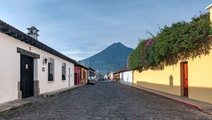 Una calle empedrada flanqueada por edificios tradicionales, con una montaña al fondo y un cielo despejado.