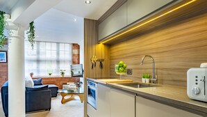 A modern kitchen with a wooden backsplash, a built-in oven, and a sink. - Cocoa Loft - York city centre studio (with parking) (York)
