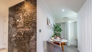 A hallway with a chalkboard wall listing local attractions and a dining area with a round table and chairs. - Cocoa Loft - York city centre studio (with parking) (York)