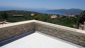 Una terrazza sul tetto con un muro in pietra e vista sul paesaggio costiero.