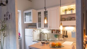 A modern kitchen with white cabinets, a stainless steel sink, and a countertop with fruits and a kettle. - Apartments Harmony 18 (Belgrade)