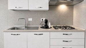 A modern kitchen with a stainless steel sink, a coffee maker, and a gas stove.