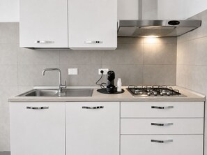 A modern kitchen with a stainless steel sink, a coffee maker, and a gas stove.