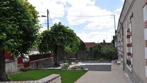 Un callejón estrecho con un pequeño jardín, un sendero empedrado y un edificio en un lado.