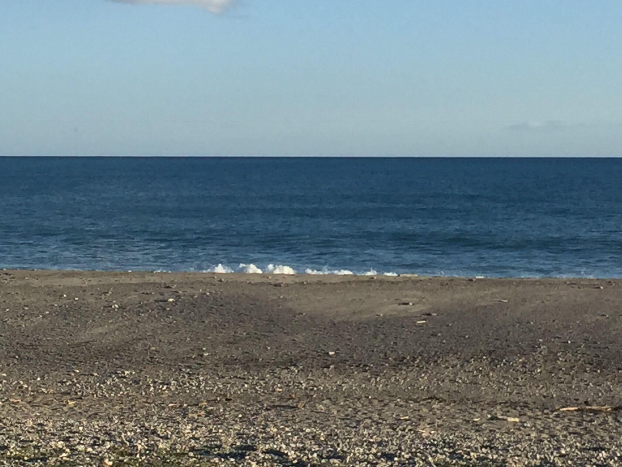 Une plage bordée d’une côte rocheuse et baignée par une mer calme.