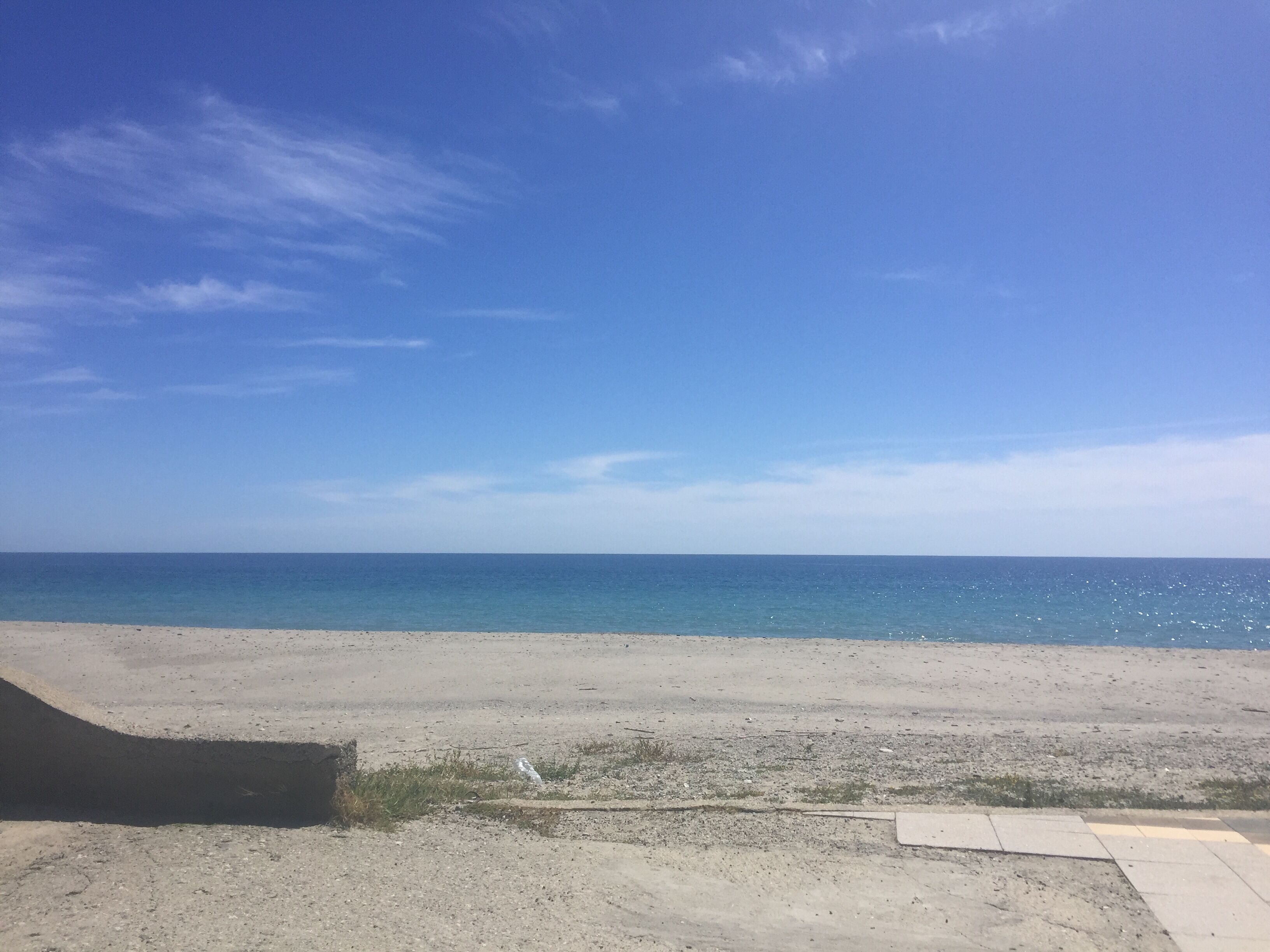 Ein Strand mit blauem Himmel und ruhiger See.