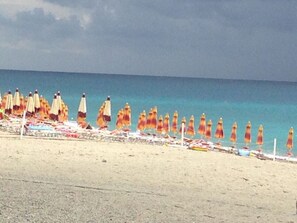 Une plage bordée de rangées de parasols et de chaises longues.