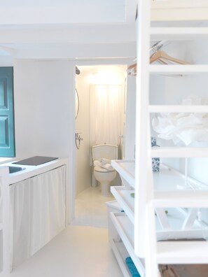 A narrow, white bathroom with a toilet, a sink, and a mirror. - Alsaki Suite Street View by K&K (Oia)