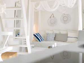 A white room with a bed, a ladder, and a woven basket. - Alsaki Suite Street View by K&K (Oia)