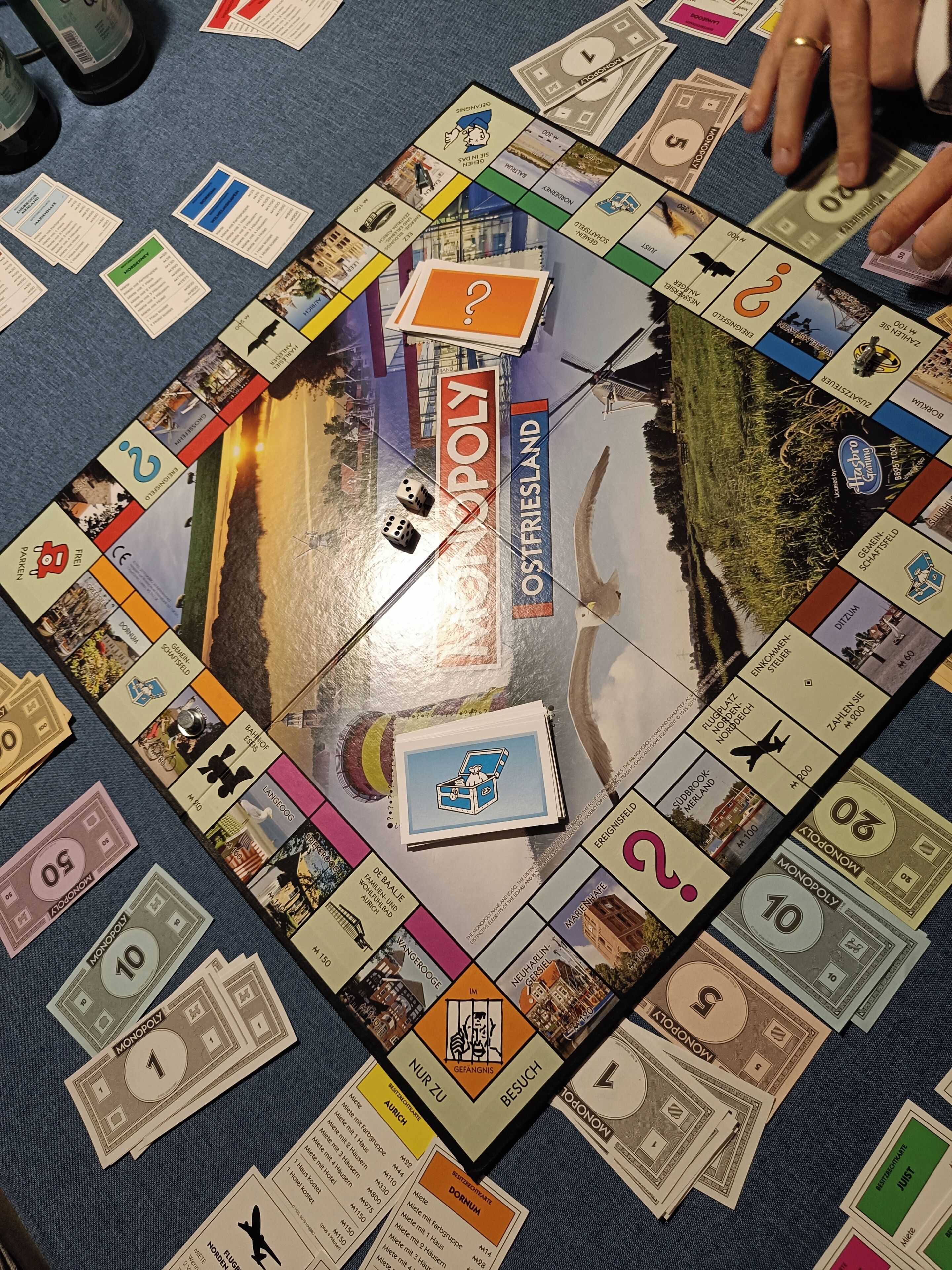 Een Monopoly spelbord met diverse eigendomskaarten en geldstukken verspreid.
