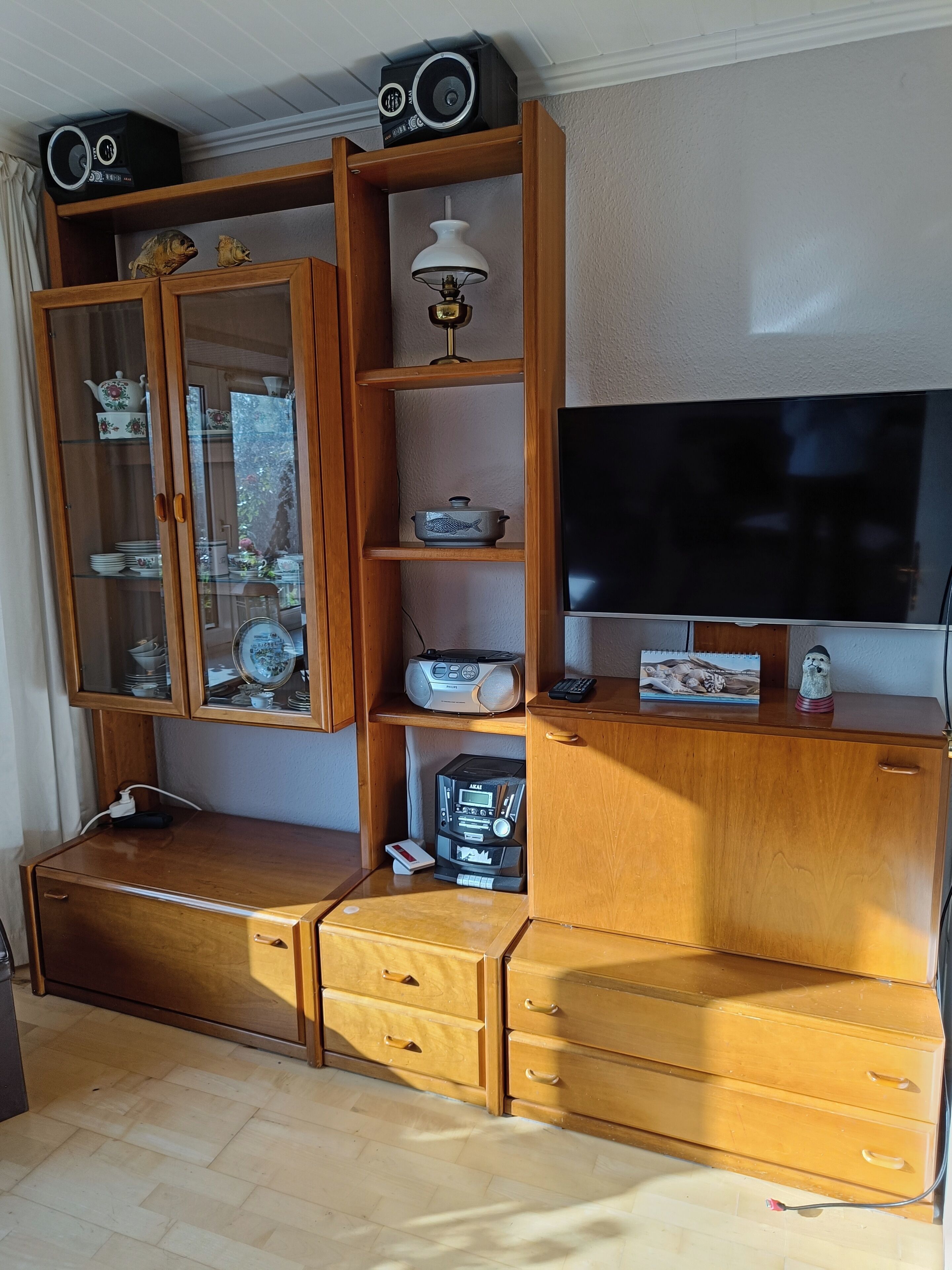 Un'unità di intrattenimento in legno con televisore, radio e oggetti decorativi.