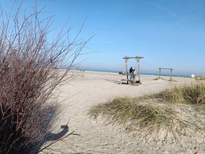 A beach with a wooden swing set and a dune.
