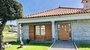 A stone building with a tiled roof, two wooden doors, and a small garden with a dog statue. - Casa da Quinta da Prelada any comfort, Pool, Terrace, Big spaces, Fafe (Rego)