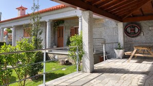 A covered outdoor area with stone columns, a wooden pergola, and a stone wall with a circular sign. - Casa da Quinta da Prelada any comfort, Pool, Terrace, Big spaces, Fafe (Rego)