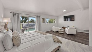 Quarto moderno com cama grande, televisão e varanda com piscina.