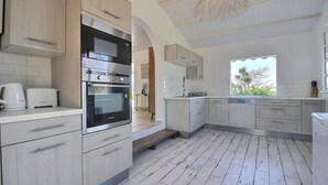 Eine moderne Küche mit hellen Holzschränken, Edelstahlgeräten und einem großen Fenster für natürliches Licht.