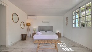 Ein Schlafzimmer mit einem Bett, einer Holzbank und einem Fenster mit Blick auf Bäume.