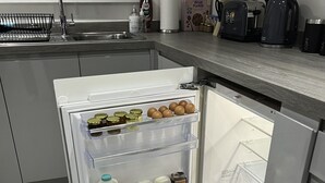 Une cuisine moderne Ă©quipĂ©e dâun rĂ©frigĂ©rateur encastrĂ©, dâun Ă©vier et dâune machine Ă cafĂ©.