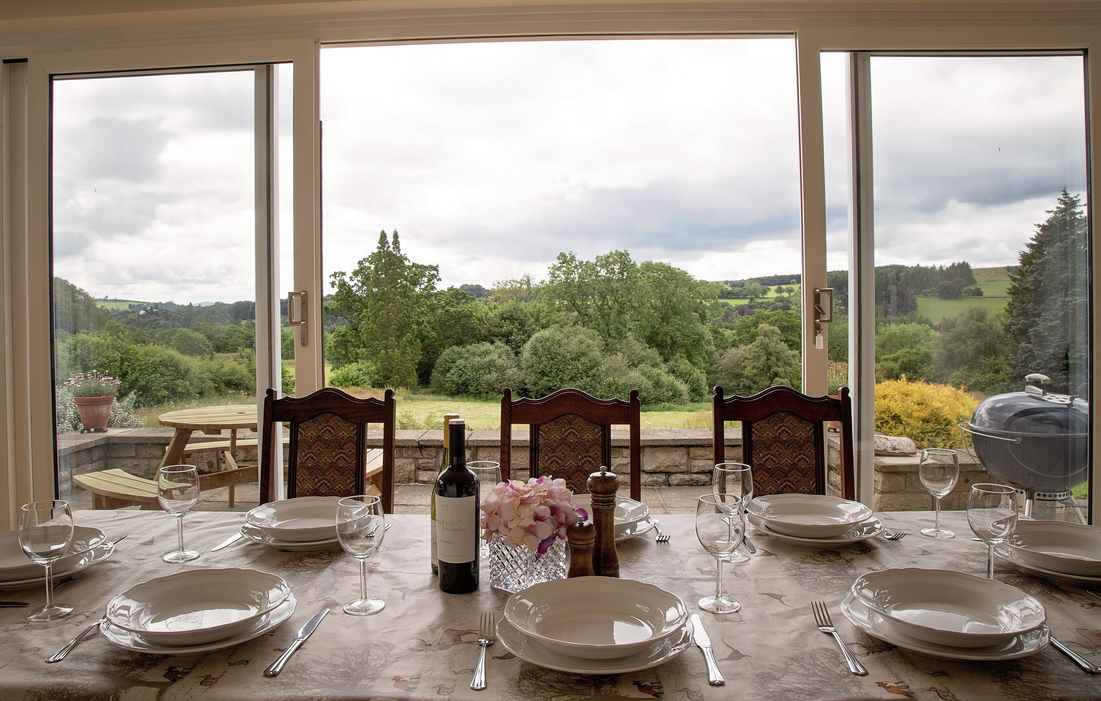 Dining conservatory with views over large mature gardens and valley beyond.
