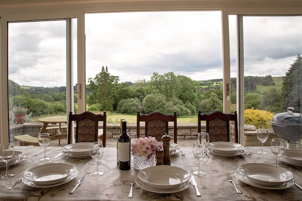 Dining conservatory with views over large mature gardens and valley beyond.