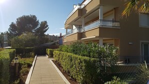 Un immeuble à plusieurs étages doté de balcons, d’une allée pavée et d’un espace vert bien entretenu.