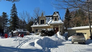 Een huis bedekt met sneeuw, met een brede oprit en een geparkeerde auto.