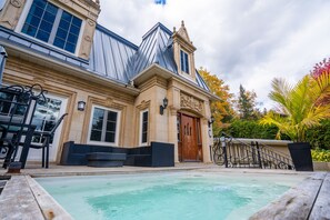 A large building with a swimming pool, outdoor seating, and a well-maintained garden.