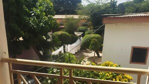 A balcony with a metal railing, a tiled floor, and yellow flowering plants. - Tobehotel (Kumasi)