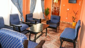 A room with blue patterned chairs, a wooden table, and orange walls. - Tobehotel (Kumasi)