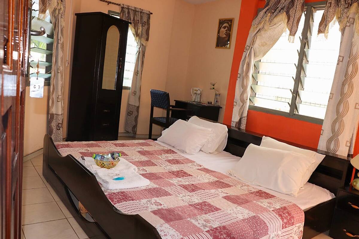 A bedroom with a bed, a wardrobe, a desk, and a chair.
