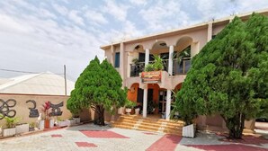 A hotel entrance with a tiled walkway, two large trees, and a sign reading "TO BE HOTEL". - Tobehotel (Kumasi)