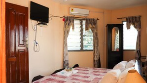 A bedroom with a bed, a television, an air conditioner, and a window with curtains. - Tobehotel (Kumasi)