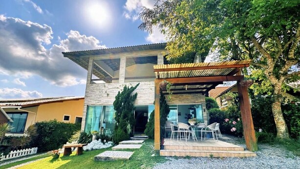 A modern house with a covered patio, a well-maintained lawn, and a clear sky. - House in the Mountains - Exclusive view! (Gravatá)