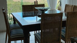 A dining area with a table and chairs, a glass-top table, and a view of a landscape through a window. - House in the Mountains - Exclusive view! (Gravatá)