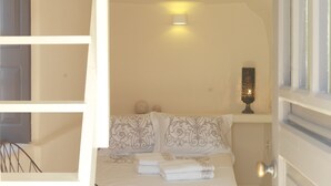 Une chambre avec un lit en mezzanine, une échelle, une table de chevet avec une lampe et un élément décoratif mural.