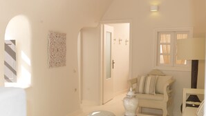 Une pièce lumineuse et bien éclairée, avec un canapé blanc, une petite table sur laquelle est posé un vase, et une décoration murale à motifs.