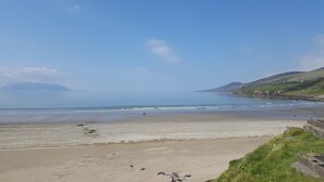 A beach with a clear sky, calm sea, and distant hills. - Relax and Refuel to the Rhythm of Nature at Fia Lodge. (Glencar)