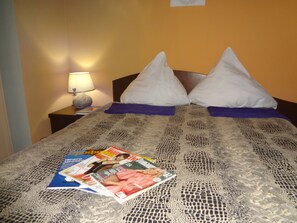Relax in comfort with a neatly arranged bed, a reading lamp, and a warm-toned wall.